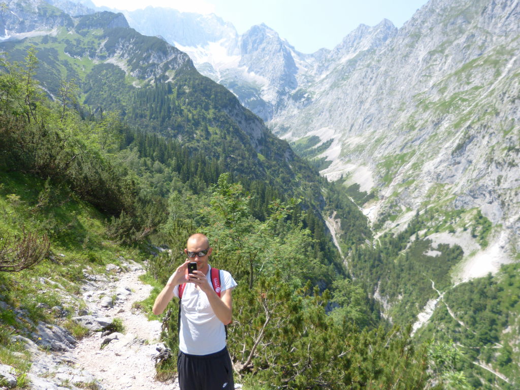 Wanderer fotografiert mit Smartphone beim Abstieg ins Höllental mit Bergpanorama