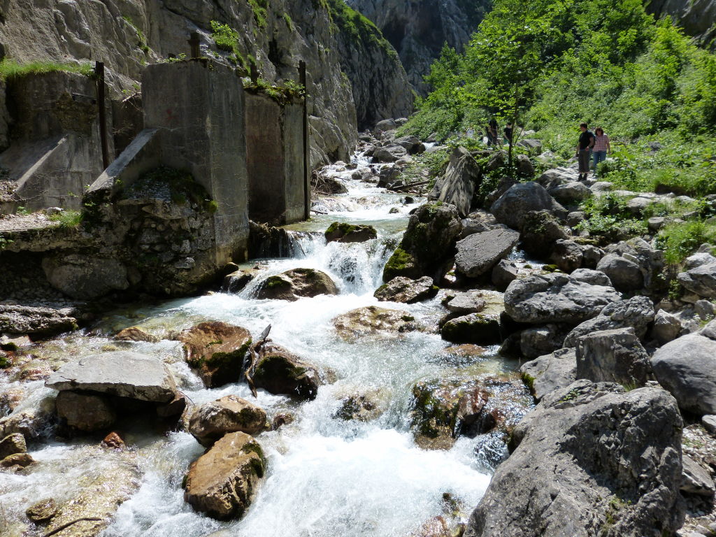Wildbach in der Höllentalklamm mit altem E-Werk und Wanderern im Hintergrund