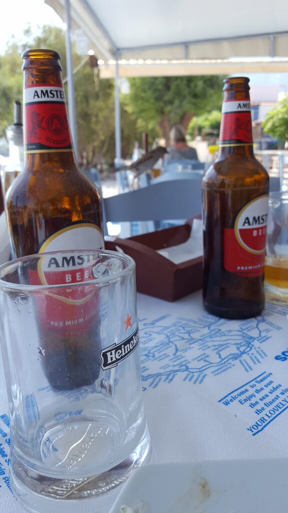 Zwei Amstel-Bierflaschen und Heineken-Glas auf Restauranttisch in Votsalakia, Samos