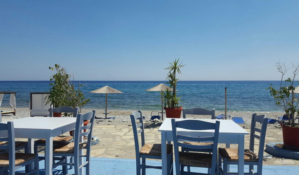 Griechisches Strandrestaurant Corali auf Samos mit weißen Tischen und Meerblick