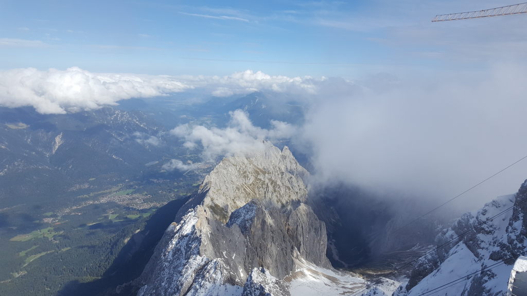 Blick vom Zugspitzgipfel auf verschneite Felsgrate und Wolken über dem Wettersteingebirge