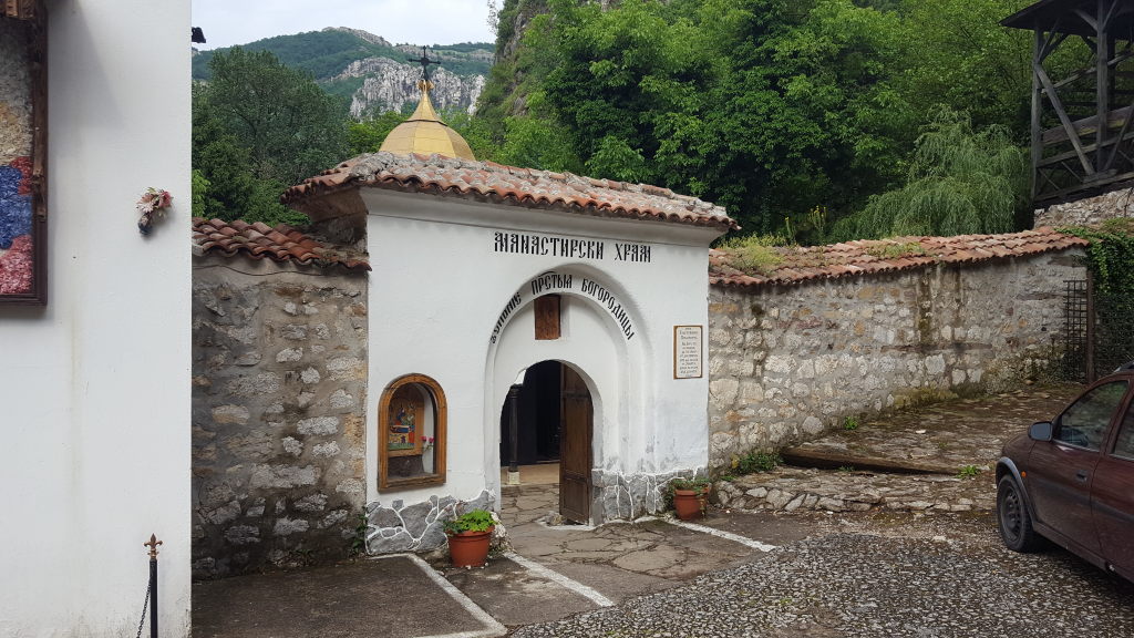 Weißes Eingangstor des Klosters Tscherepisch mit kyrillischer Inschrift und goldener Kuppel