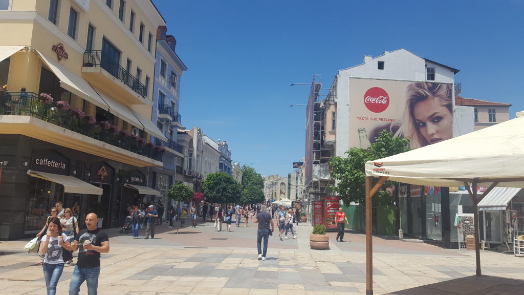 Belebte Fußgängerzone in Plovdiv mit Cafés und Coca-Cola-Werbeplakat