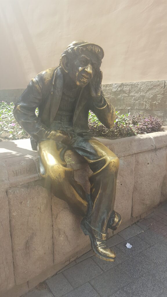 Bronzestatue des Milyo sitzend auf einer Mauer in Plovdiv