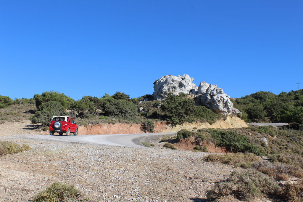 Roter Jeep auf Schotterweg mit weißem Felsformation auf Kos, Griechenland