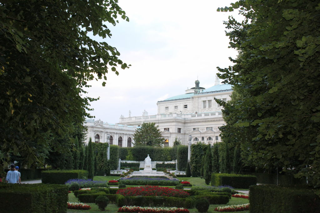 Blick durch den Volksgarten Wien auf das Burgtheater mit Blumenbeeten und Statue