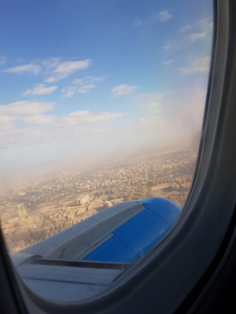 Blick aus dem Flugzeugfenster auf eine dunstbedeckte Großstadt in Ägypten