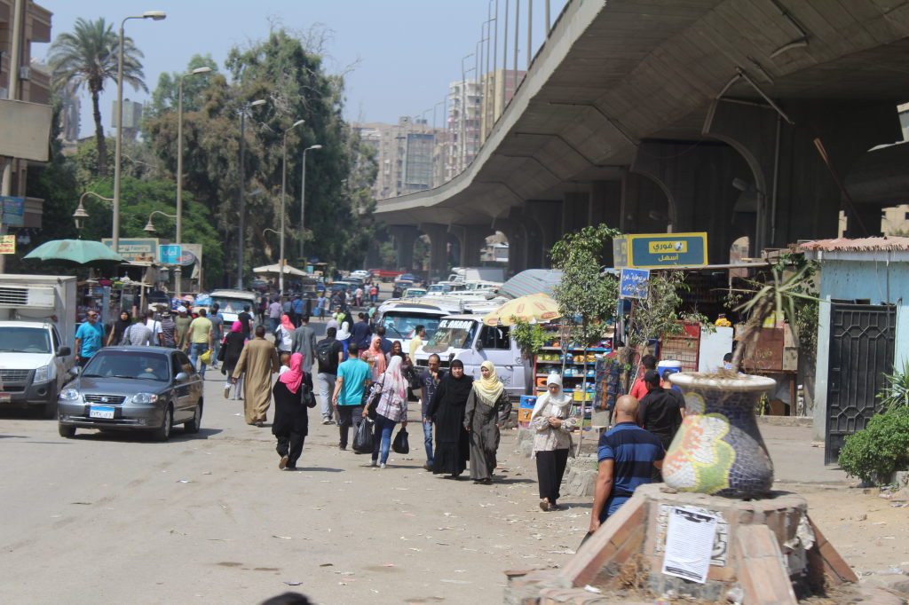 Belebte Straße in Kairo mit Fußgängern und Straßenhändlern unter einer Hochstraße