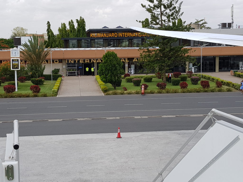 Kilimanjaro International Airport Terminal mit Schriftzug und gepflegtem Vorplatz, Tansania