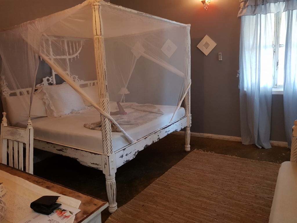 Weißes Himmelbett mit Moskitonetz in einem Hotelzimmer auf Sansibar