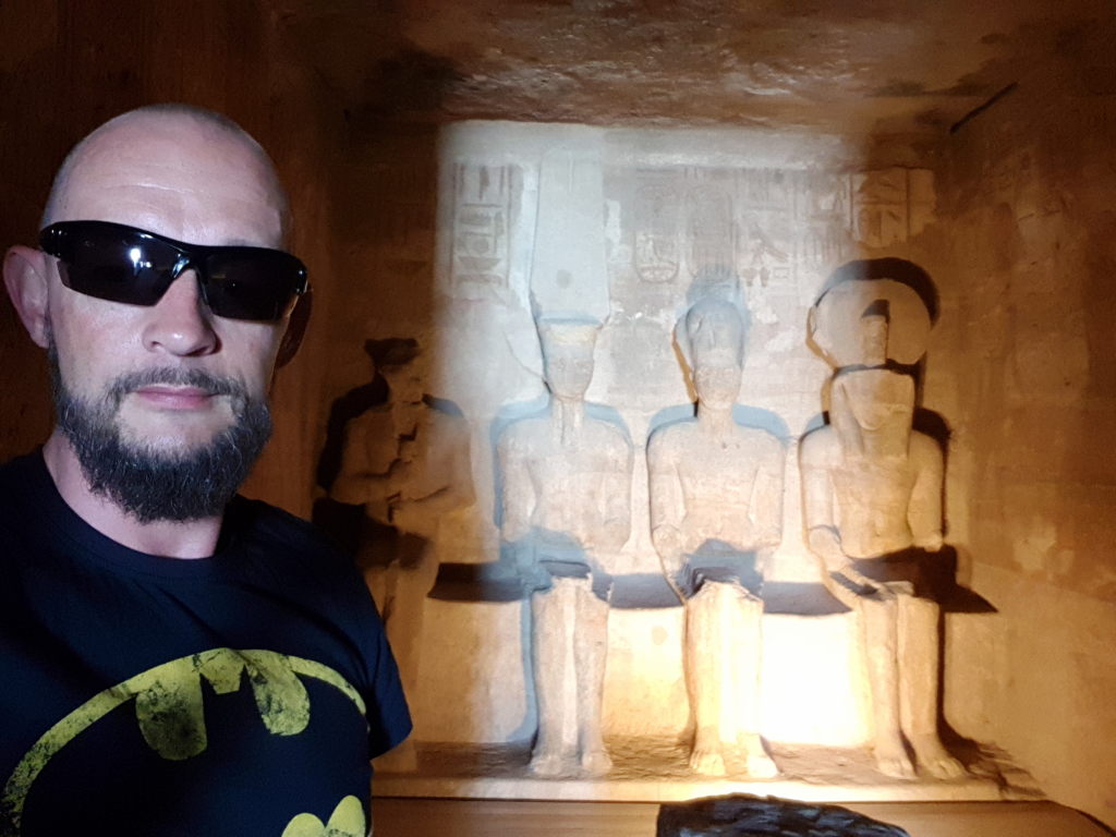 Selfie eines Mannes mit Sonnenbrille vor beleuchteten altägyptischen Götterstatuen in Abu Simbel