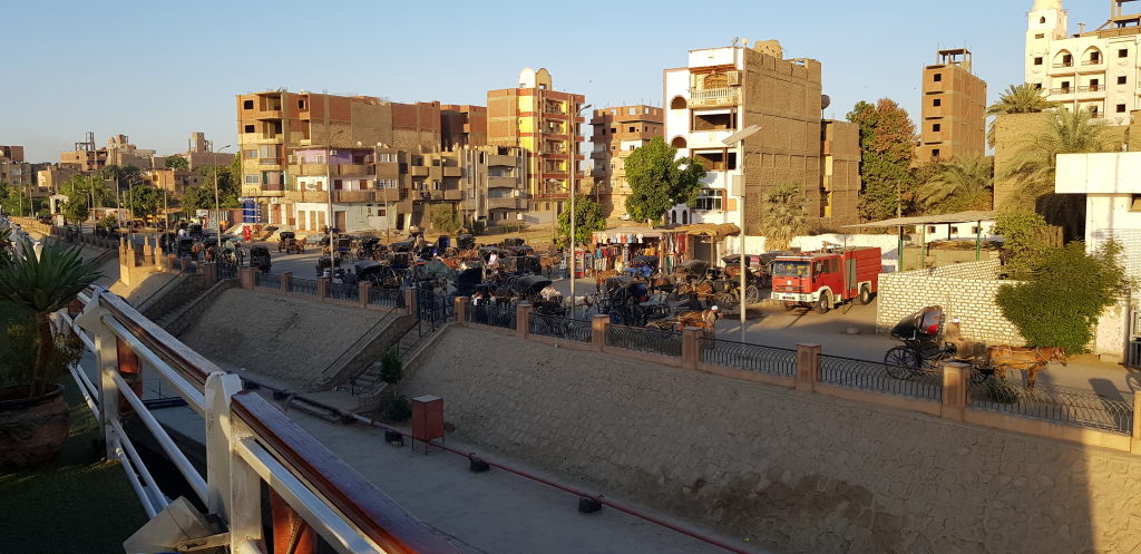 Stadtansicht von Edfu mit Pferdekarren und Häusern entlang des Nilufers