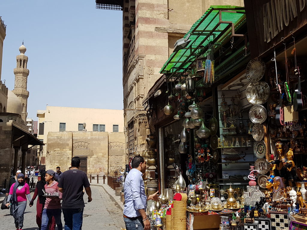 Belebte Gasse im Basar Khan el-Khalili in Kairo mit Souvenirläden und Minarett