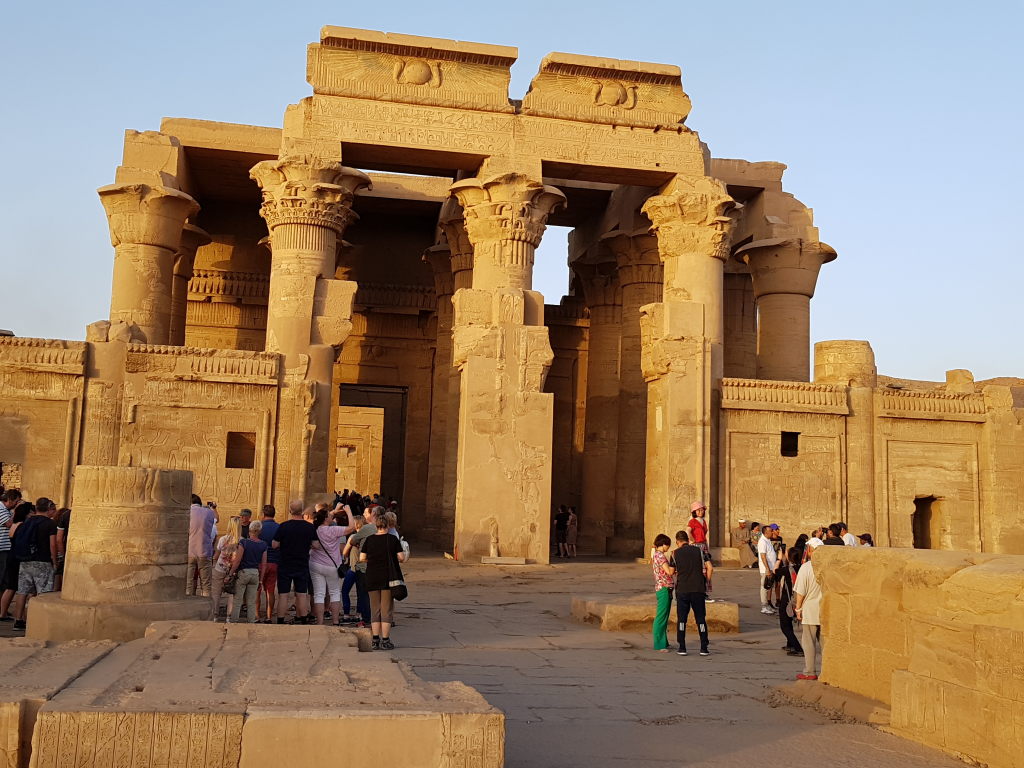 Touristen vor dem imposanten Eingang des Kom-Ombo-Tempels in Ägypten im Abendlicht