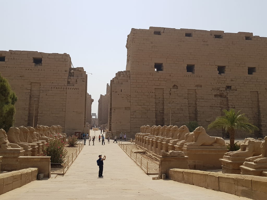 Sphinxallee am Eingang des Karnak-Tempels in Luxor mit Touristen und mächtigen Pylonen
