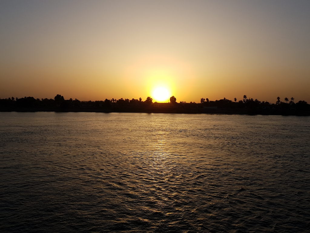 Goldener Sonnenuntergang über dem Nil bei Luxor mit Palmen-Silhouette