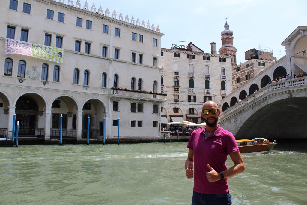Mann mit Sonnenbrille vor der Rialtobrücke in Venedig am Canal Grande