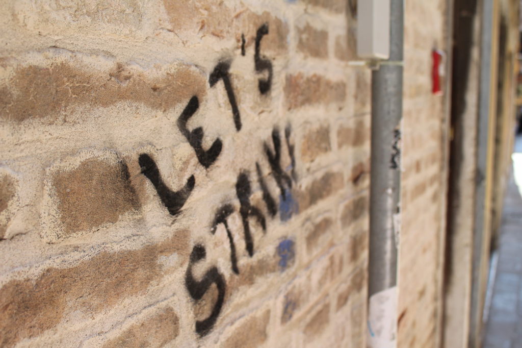 Graffiti "Let's Stay" auf Backsteinmauer in Venedig