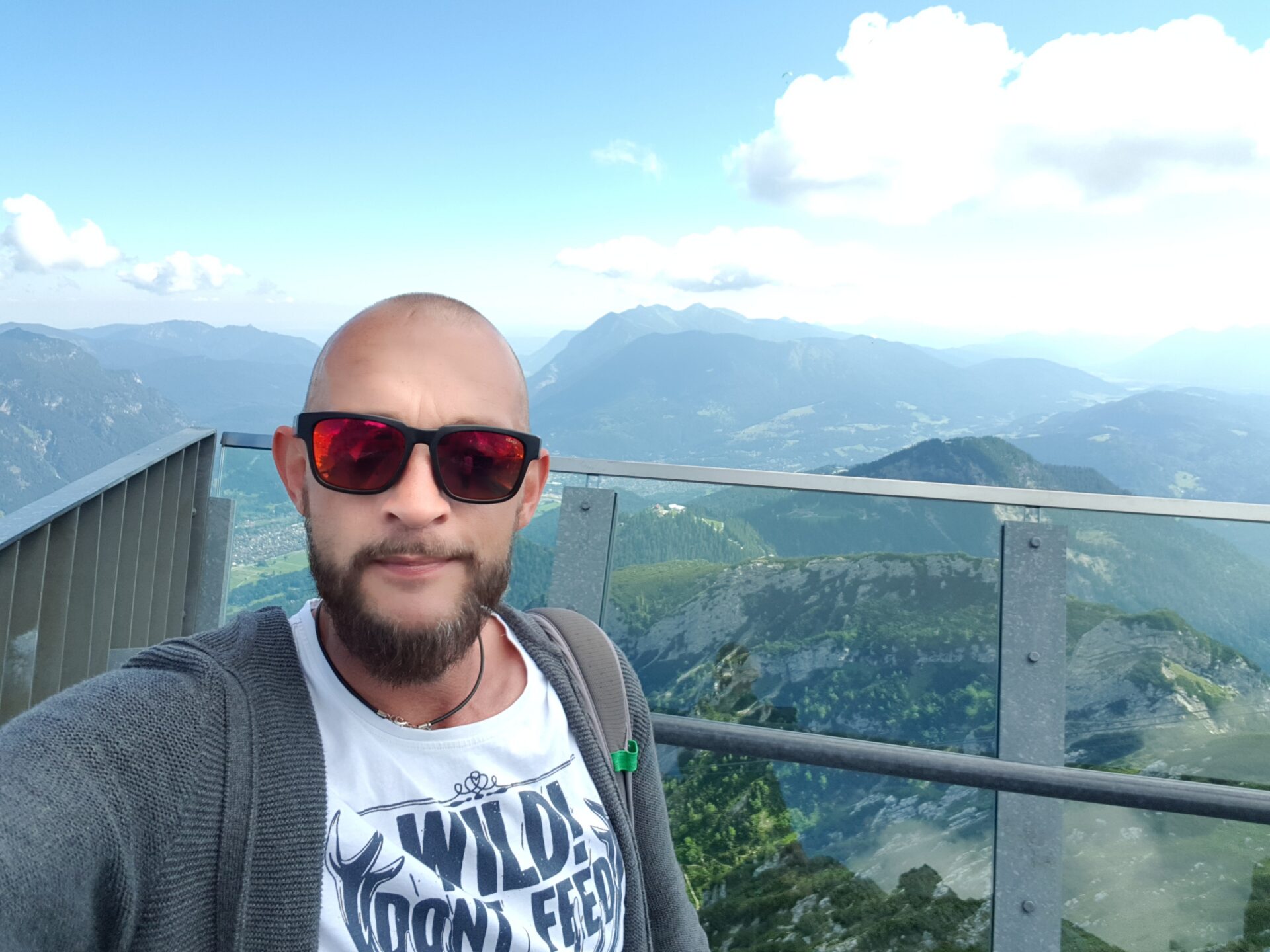 Mann mit Sonnenbrille macht Selfie auf der Alpspix-Aussichtsplattform mit Alpenpanorama
