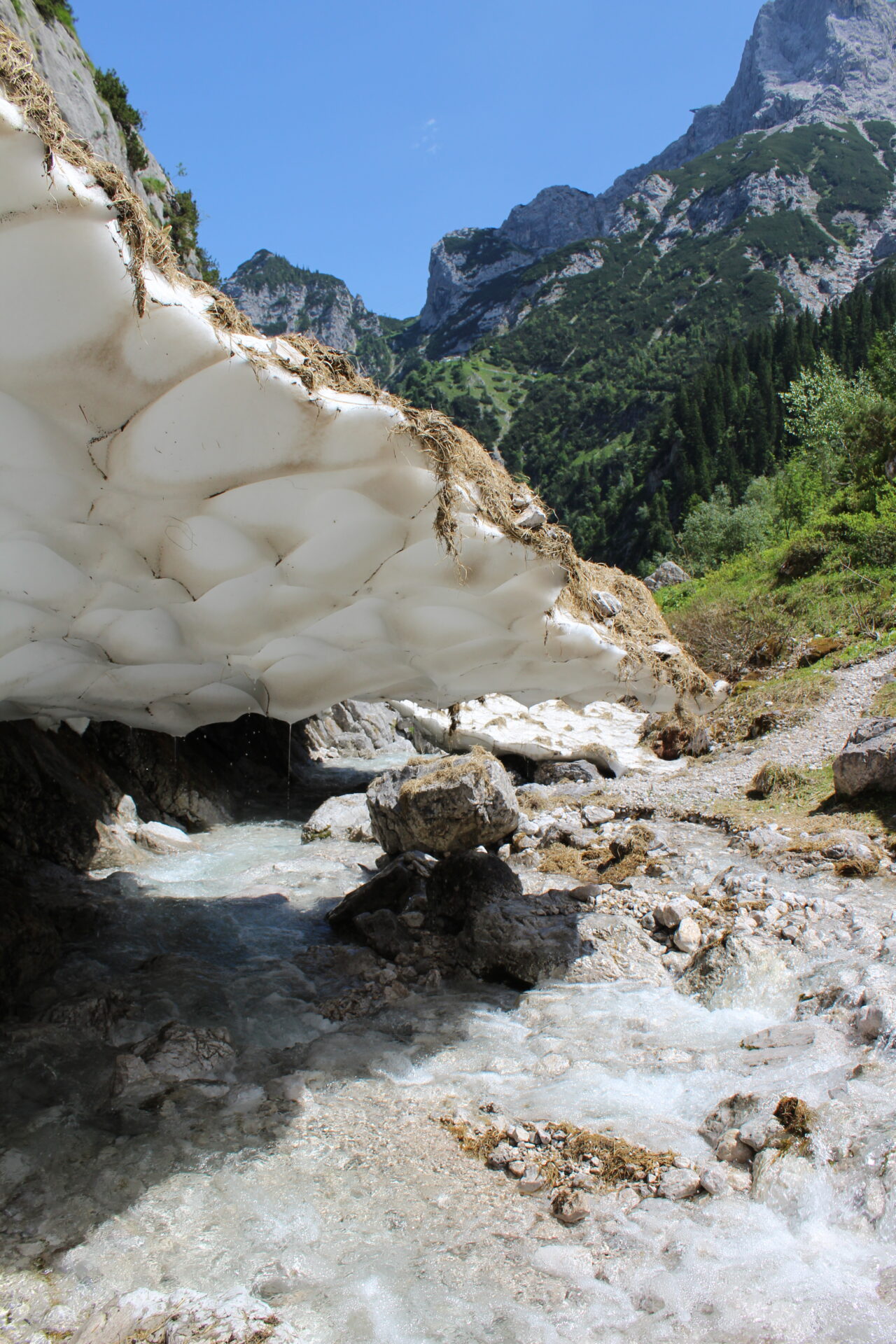 Schmelzender Schneebogen über rauschenden Gebirgsbach in der Höllentalklamm