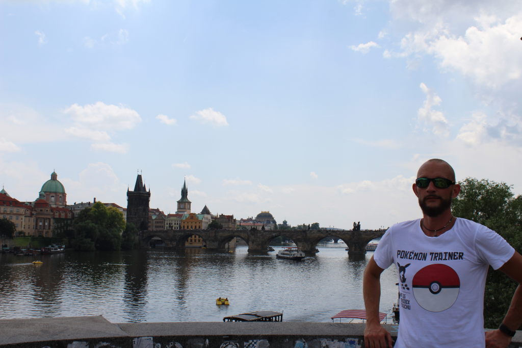 Mann mit Pokemon-Trainer-Shirt vor der Karlsbrücke und Moldau in Prag