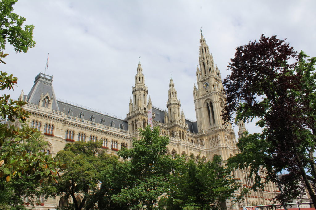 Wiener Rathaus mit neugotischen Türmen hinter sommerlichen Bäumen