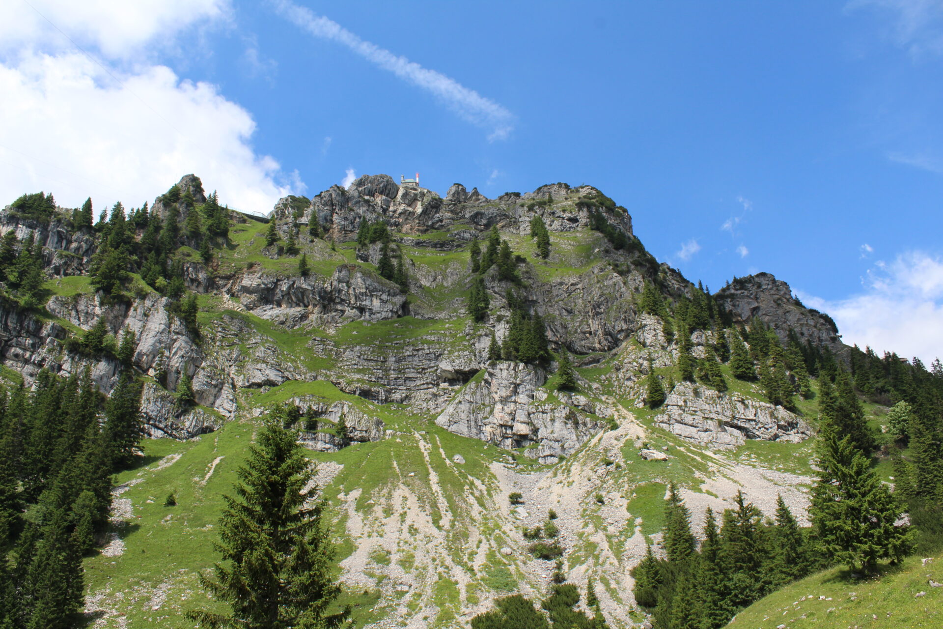 Blick von unten auf den felsigen Wendelstein-Gipfel mit Observatorium und Tannen