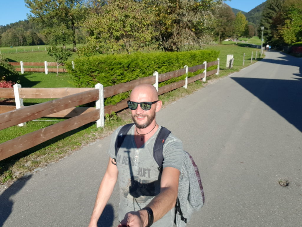 Wanderer mit Sonnenbrille und Rucksack auf Landstraße bei Tratenbach im Herbst