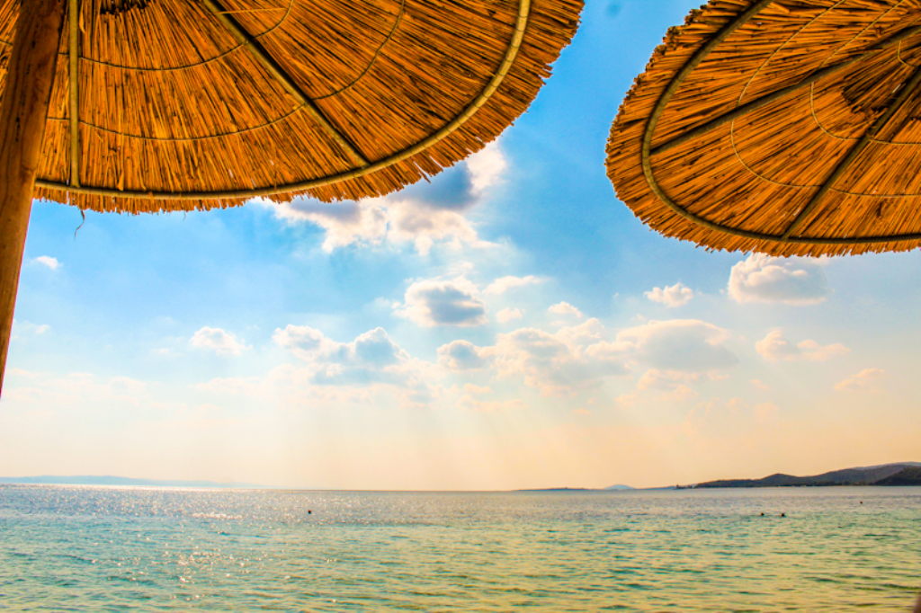 Zwei Strohschirme am Toroni Beach in Nikiti mit Blick aufs Meer und blauen Himmel