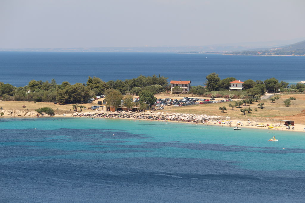 Toroni Beach Halkidiki mit türkisblauem Wasser, Sonnenschirmen und Strandbar aus der Vogelperspektive