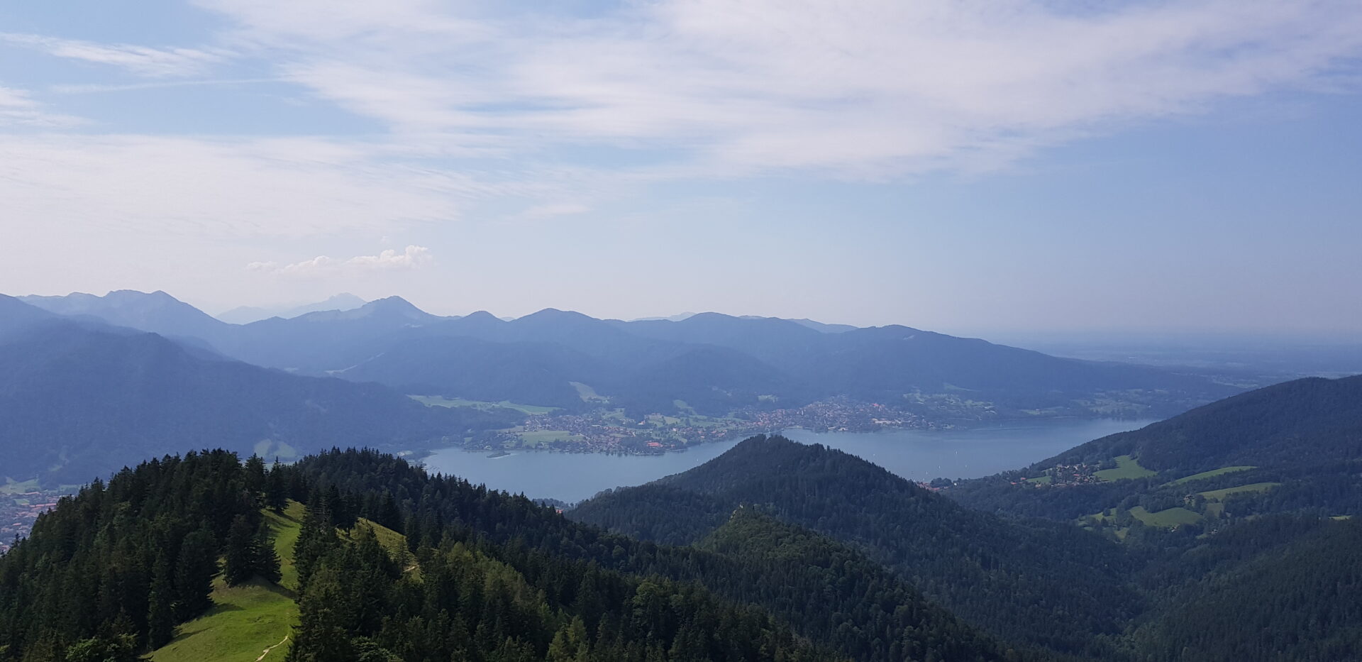 Weitreichendes Panorama vom Baumgartenschneid auf den Tegernsee mit dem Ort Tegernsee am Ufer und Bergketten im Hintergrund