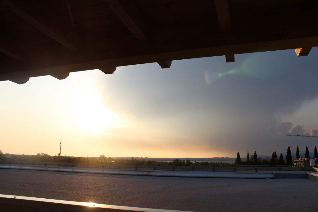 Sonnenuntergang am Gardasee, Blick von einer Terrasse mit Holzdach auf Zypressen und See