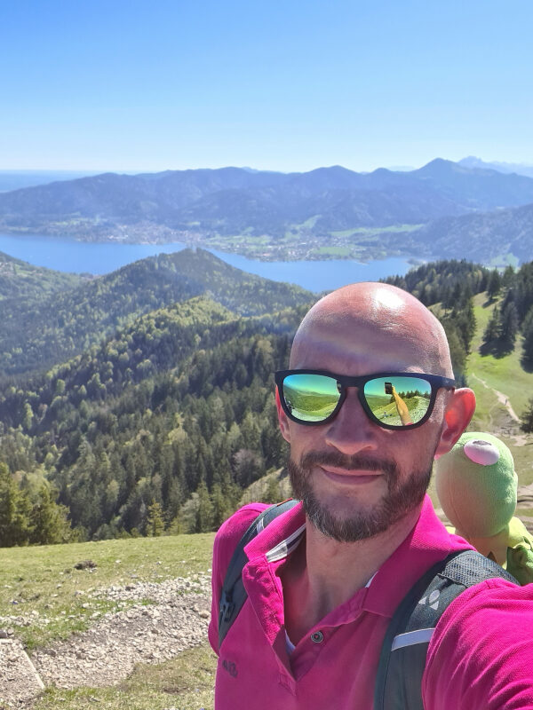 Sebastian mit Kermit auf dem Gipfel des Baumgartenschneid, Schliersee im Hintergrund