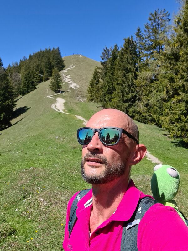 Sebastian mit Kermit am Rucksack, dahinter der steile Weg zum Baumgartenschneid-Gipfel