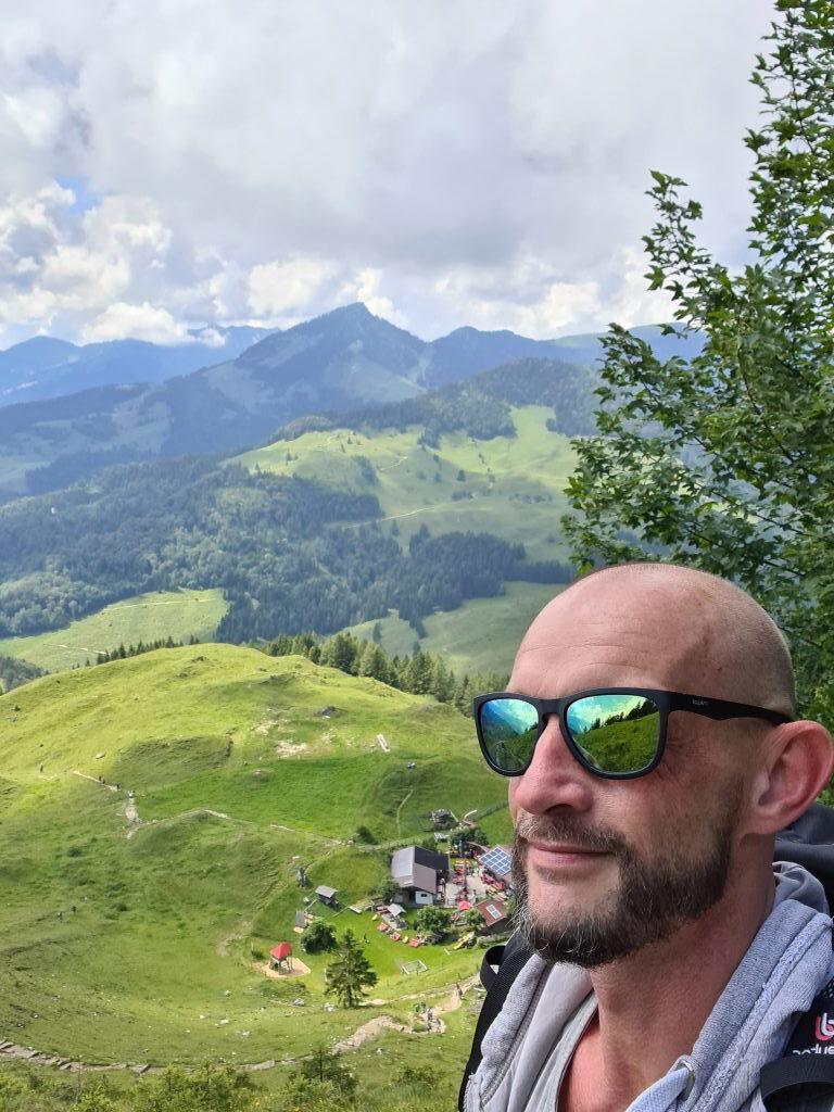 Selfie beim Abstieg vom Kranzhorn mit Blick auf Alm und Bergketten im Hintergrund Juli 2020