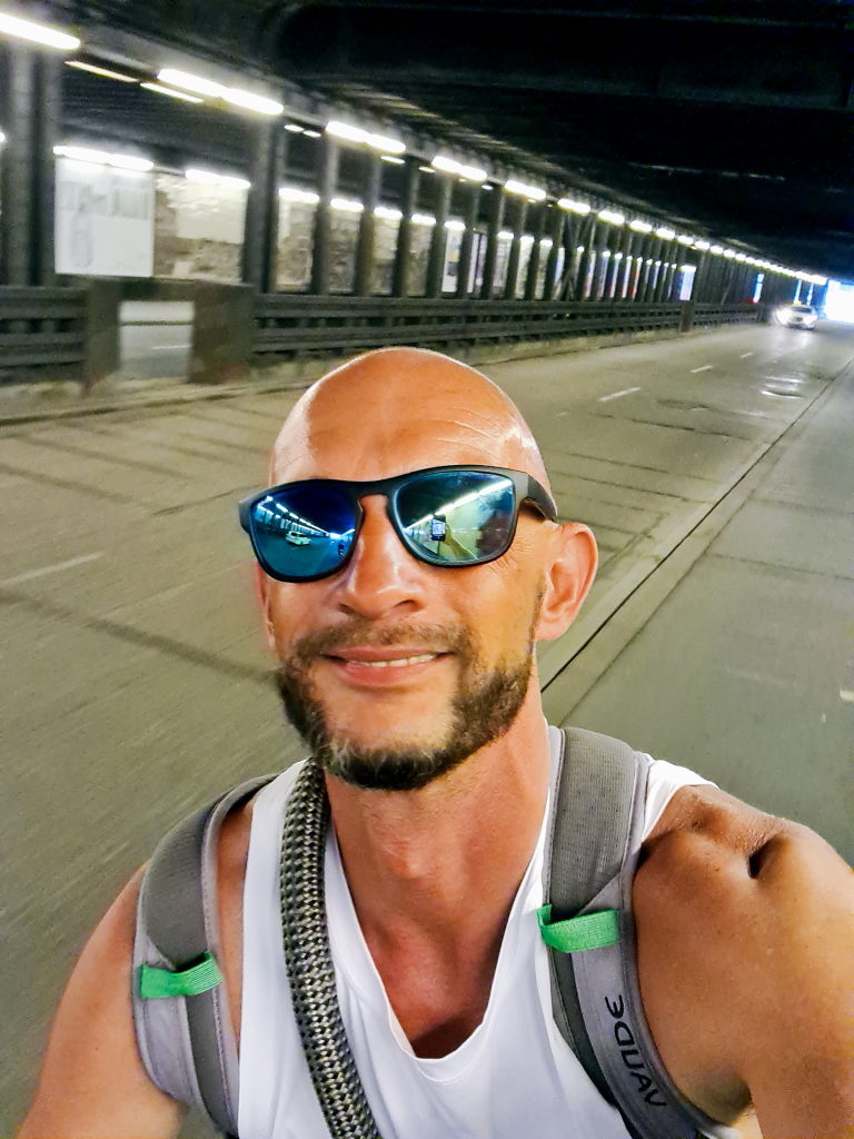 Sebastian Selfie in einer langen Münchner Unterführung mit Rucksack, Tunnellichter im Hintergrund, August 2020