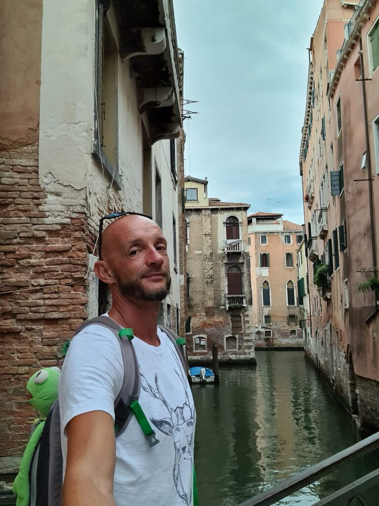 Sebastian mit Kermit auf dem Rücken an einem Kanal in Venedig, August 2020