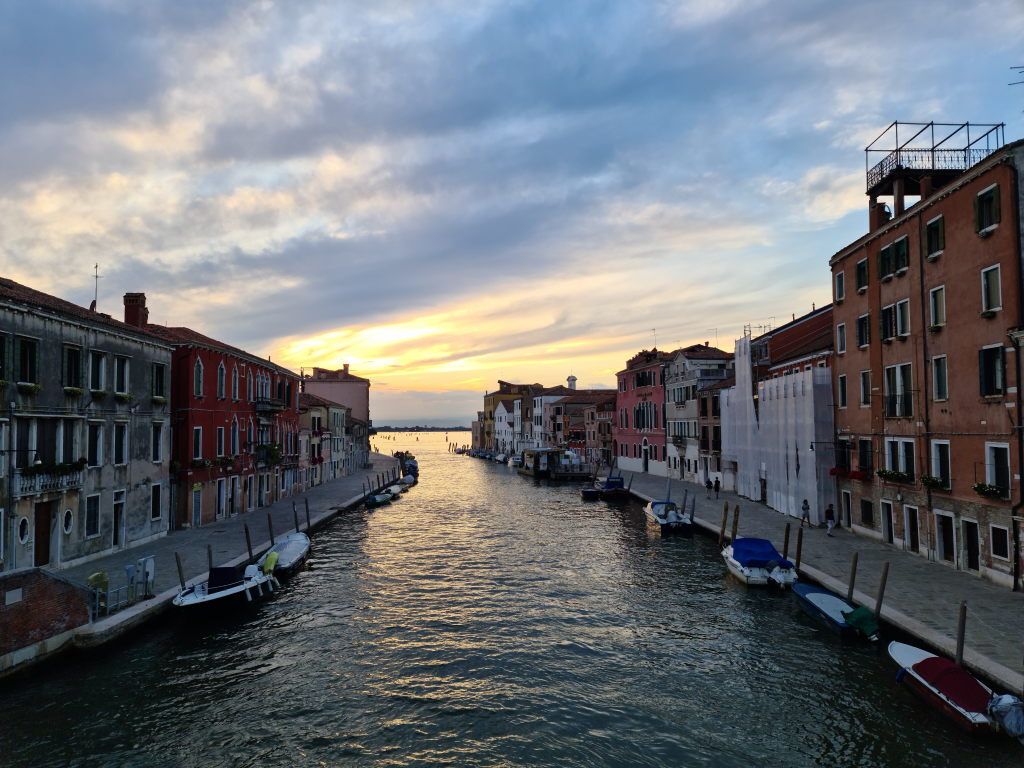 Sonnenuntergang über einem Kanal in Venedig mit bunten Häuserfassaden, August 2020