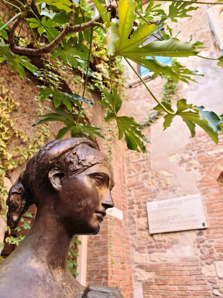 Nahaufnahme der Bronzestatue von Julia im Innenhof der Casa di Giulietta in Verona unter Feigenbaum und Efeu