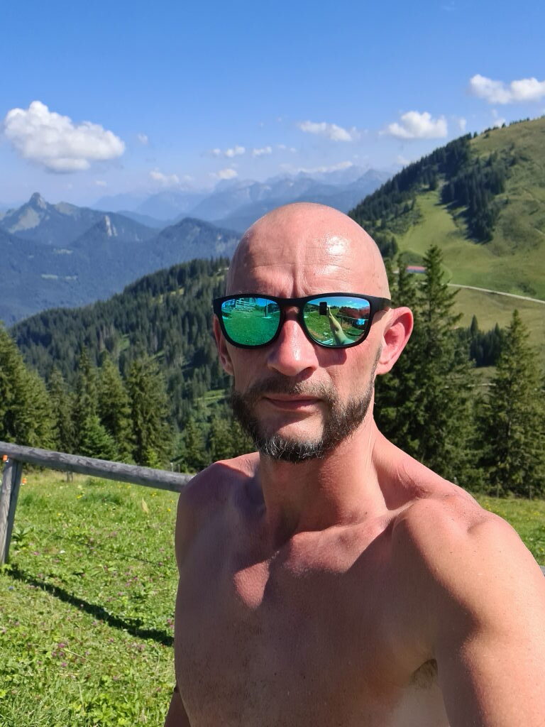 Sebastian oben ohne, verschwitzt, mit Sonnenbrille, Selfie am Wallberg mit Bergpanorama