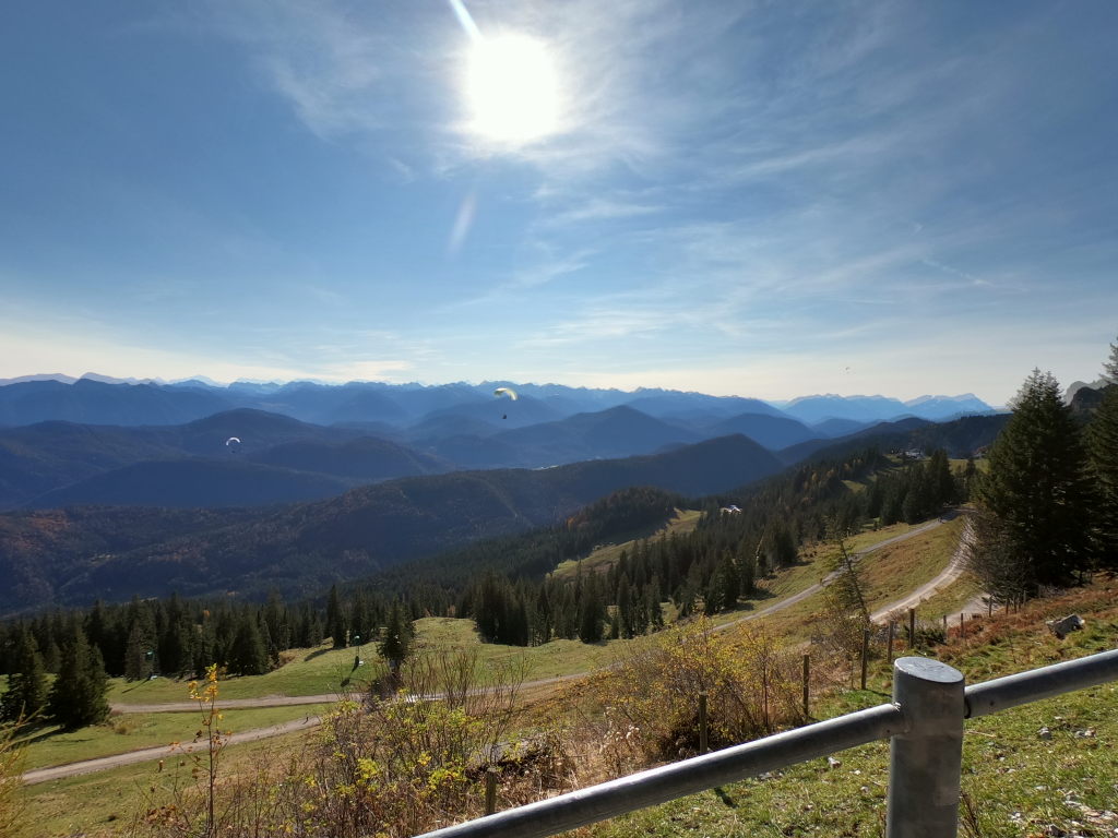 Paragleiter über dem Brauneck mit weitem Alpenvorlandpanorama und Paraglider im Oktober 2020