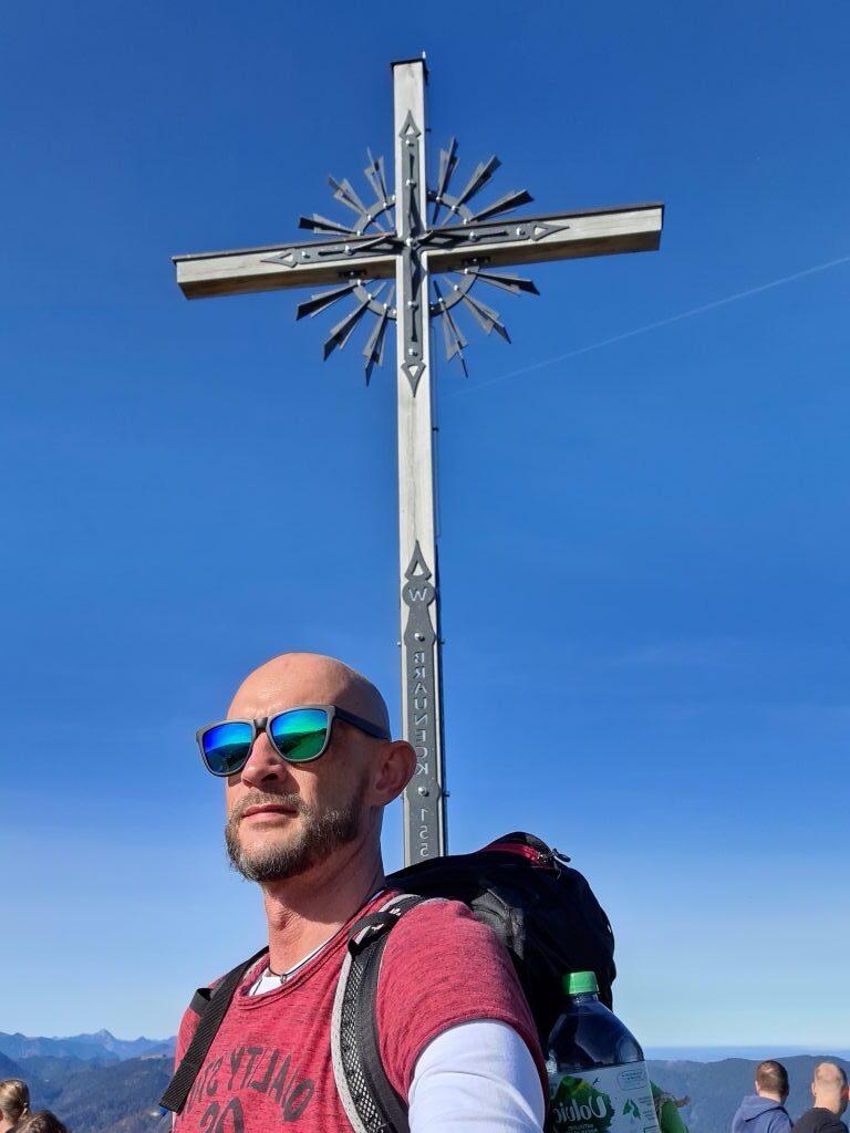 Wanderer vor dem Gipfelkreuz am Brauneck im Oktober 2020