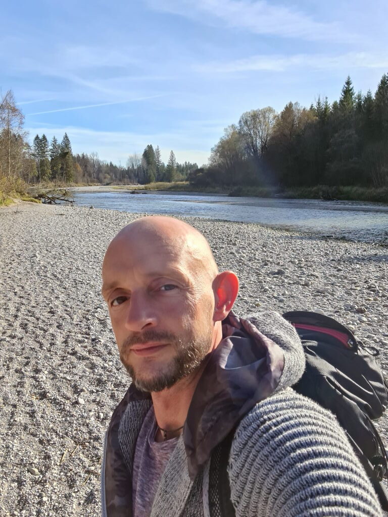 Sebastian als Selfie am Isarkiesufer bei Schäftlarn, Rucksack, Fluss im Hintergrund