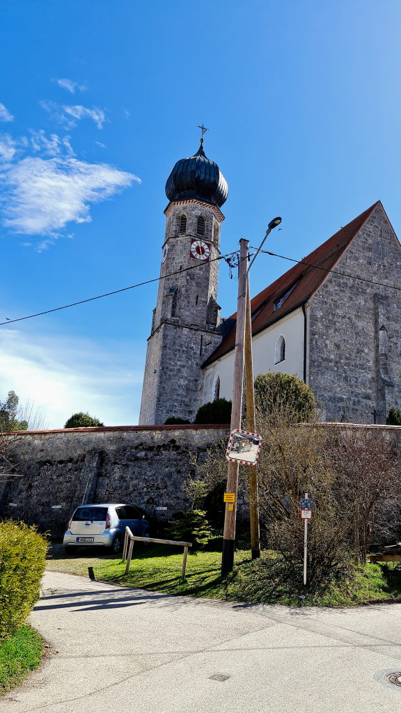 Warngau Dorfkirche mit dunklem Zwiebelturm vor blauem Aprilhimmel