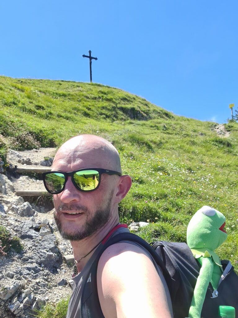 Sebastian und Kermit im Selfie kurz unterhalb des Gipfelkreuzes am Baumgartenschneid bei blauem Himmel