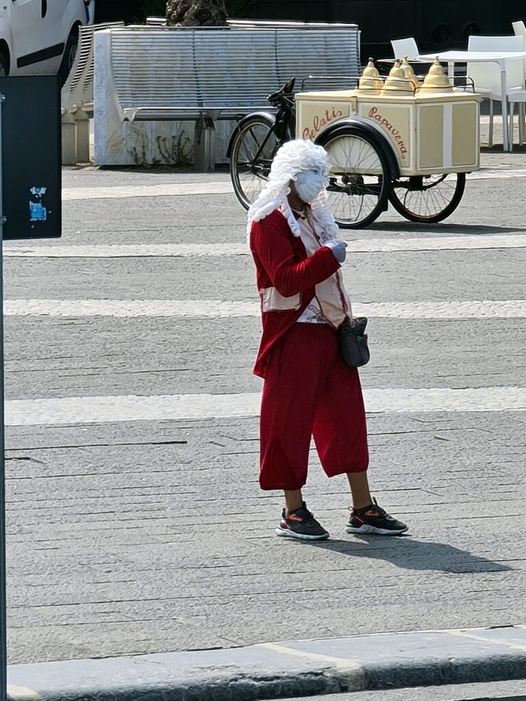 Verkleidete Person als Weihnachtsmann mit weißer Perücke und rotem Anzug auf einer Piazza in La Spezia, Juli 2021
