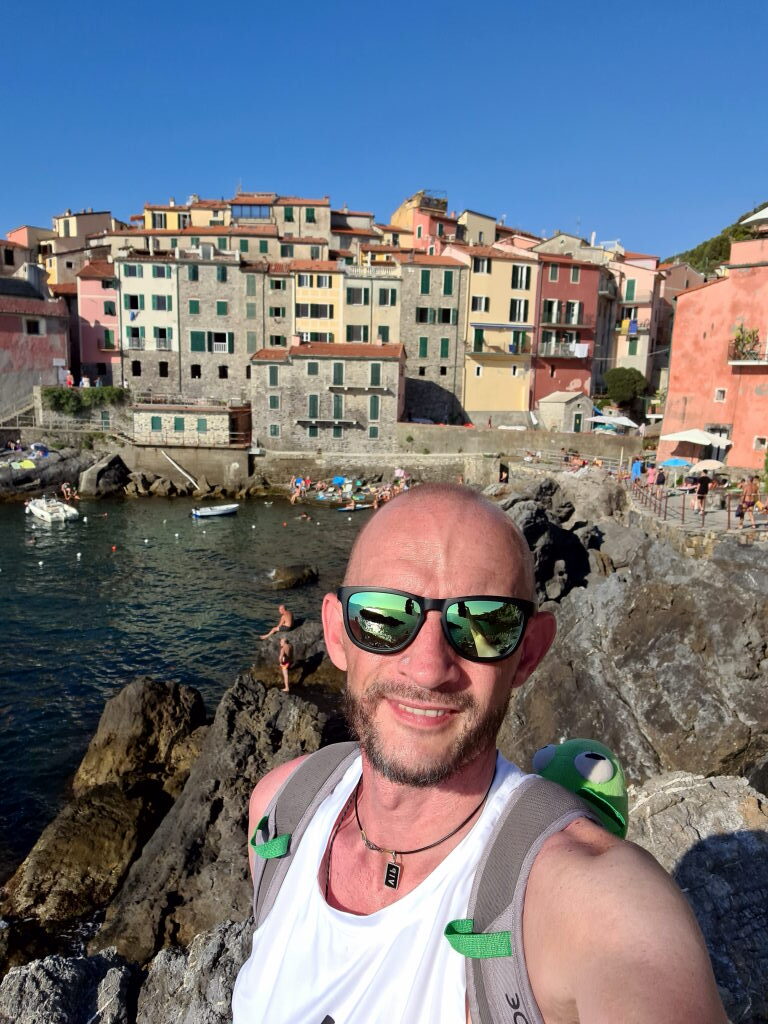 Selfie an der Marina von Tellaro mit bunten Häusern und Bucht im Hintergrund, Juli 2021