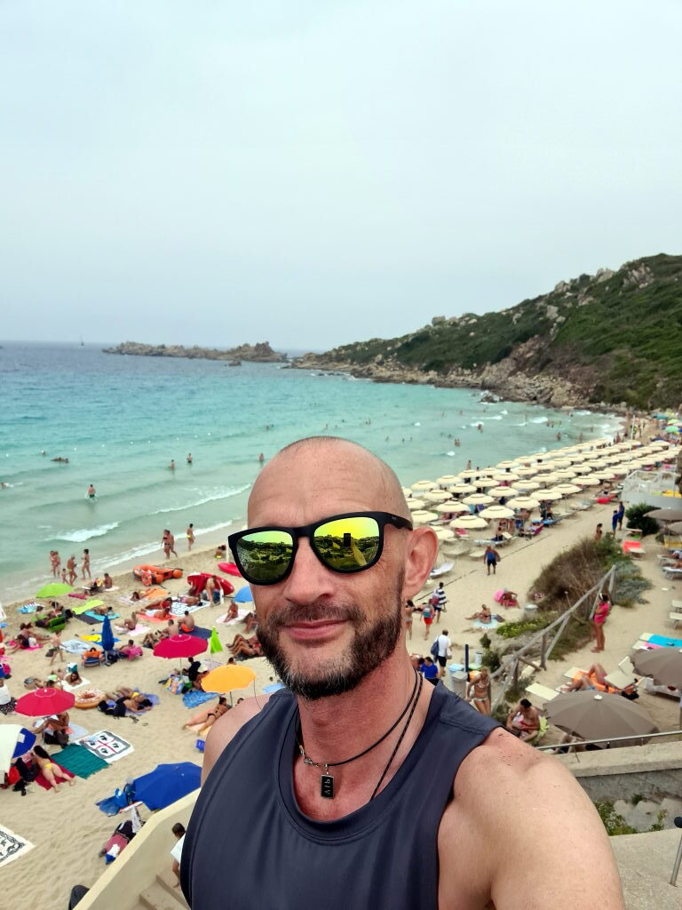 Selfie von Sebastian am Strand Spiaggia Rena Majori auf Sardinien, Sonnenbrille, türkises Meer im Hintergrund