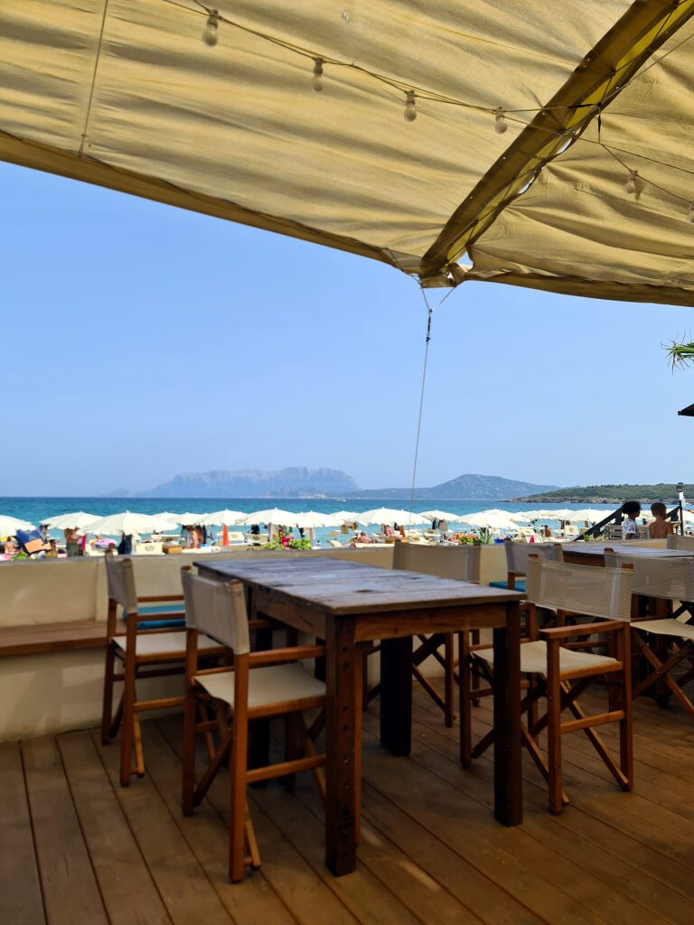 Terrasse eines Strandrestaurants an der Spiaggia Pittulongu mit Blick auf Strand, Meer und Isola Tavolara