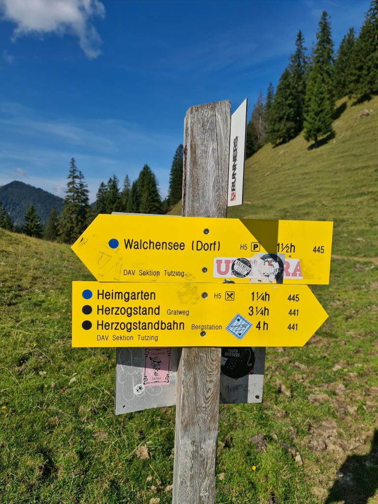 Gelber DAV-Wanderwegweiser mit Zielen Walchensee, Heimgarten, Herzogstand und Herzogstandbahn, September 2021